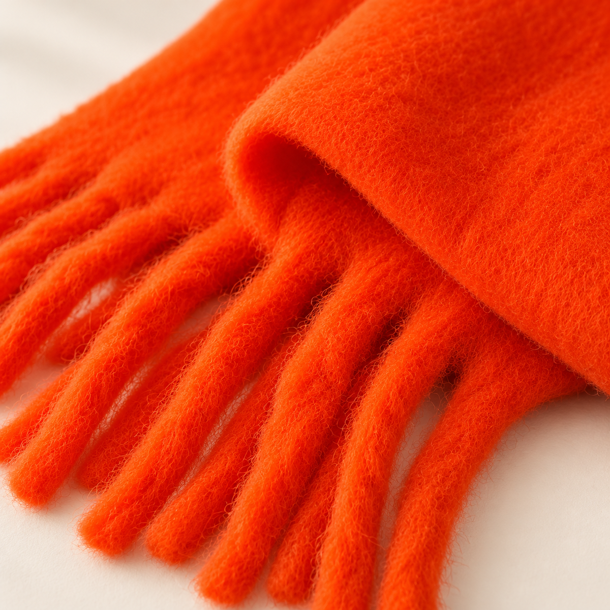 Détail matière douce et franges de l’écharpe orange mandarine